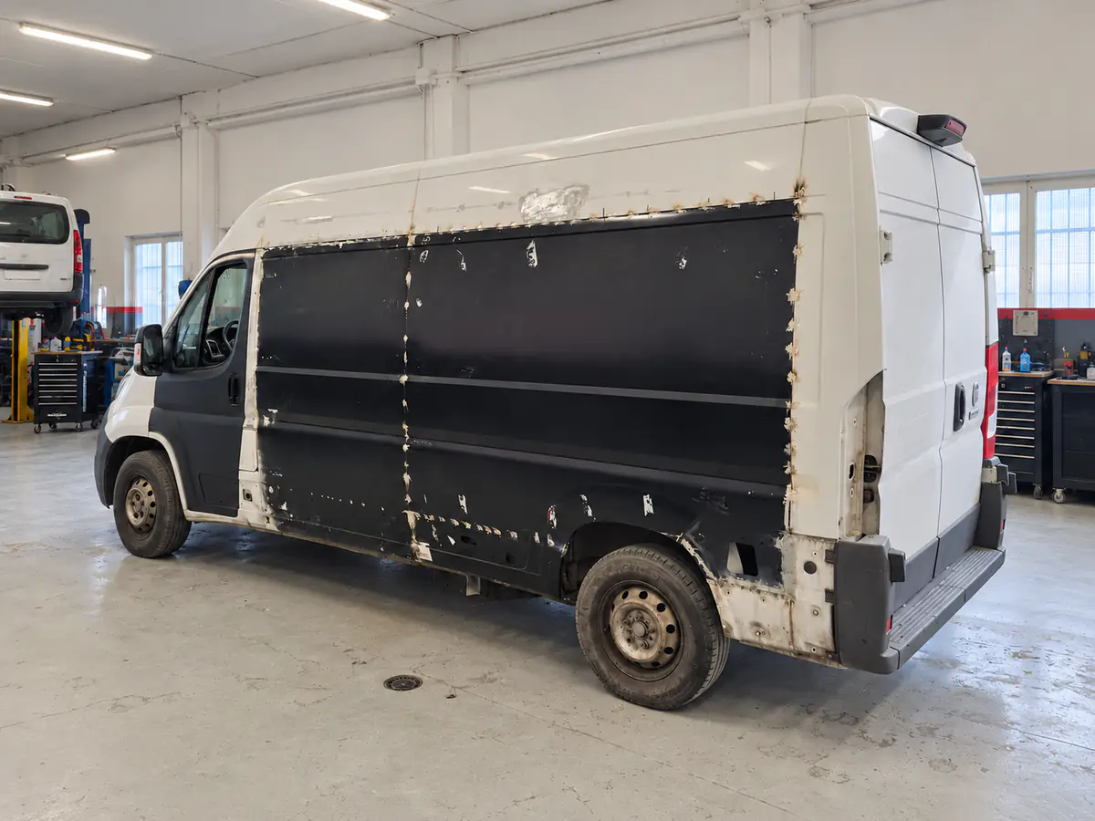 Fase 1: furgone bianco appena arrivato in carrozzeria, con le vecchie pannellature nere sulla fiancata
